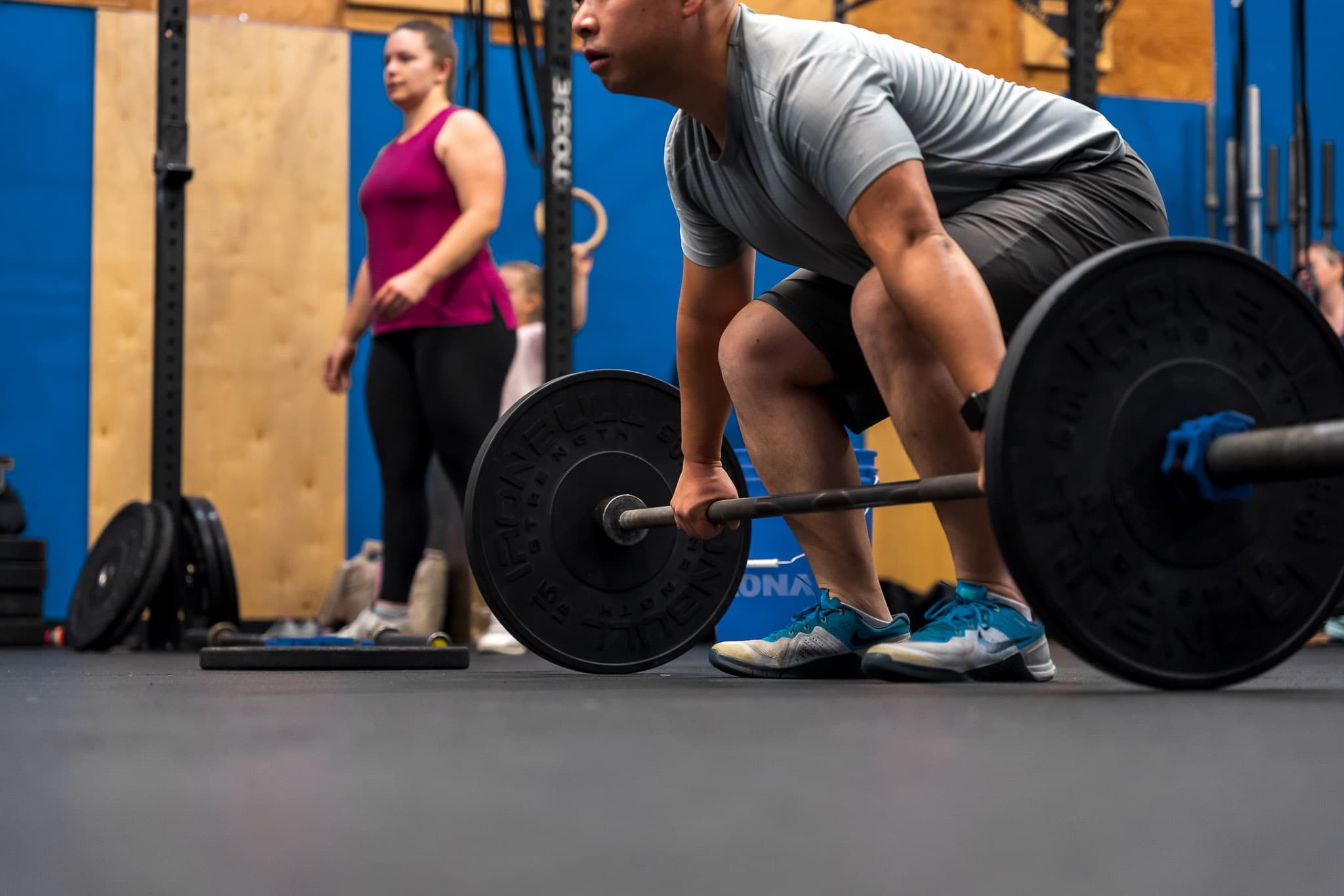 A member setting up for a barbell deadlift with a coach nearby at Overdrive Athletic Club in Richmond, BC