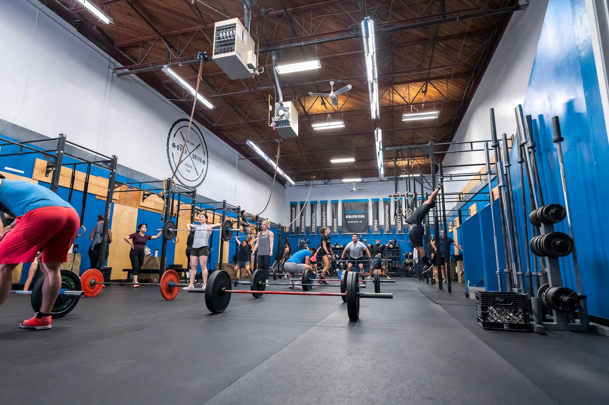 A wide view of a CrossFit class training with barbells and rings at Overdrive Athletic Club in Richmond, BC